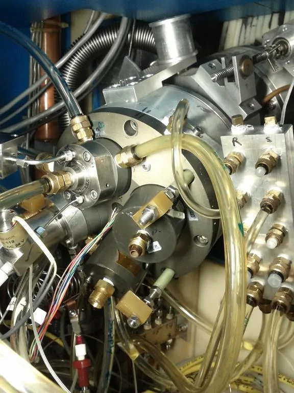 A regular liquid water target mounted on the target selector of TRIUMF's TR13 cyclotron, surrounded by cooling lines, valves, and signal wiring.